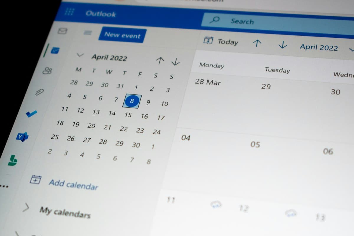Close-up layar laptop menampilkan kalender digital Outlook dengan tanggal dan jadwal mingguan.