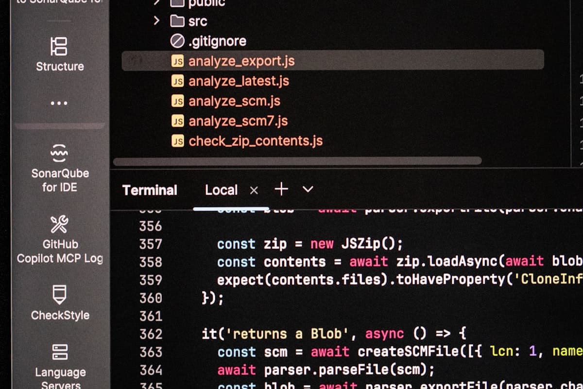 Layar komputer menampilkan kode dan output terminal pemrograman di ruangan gelap.