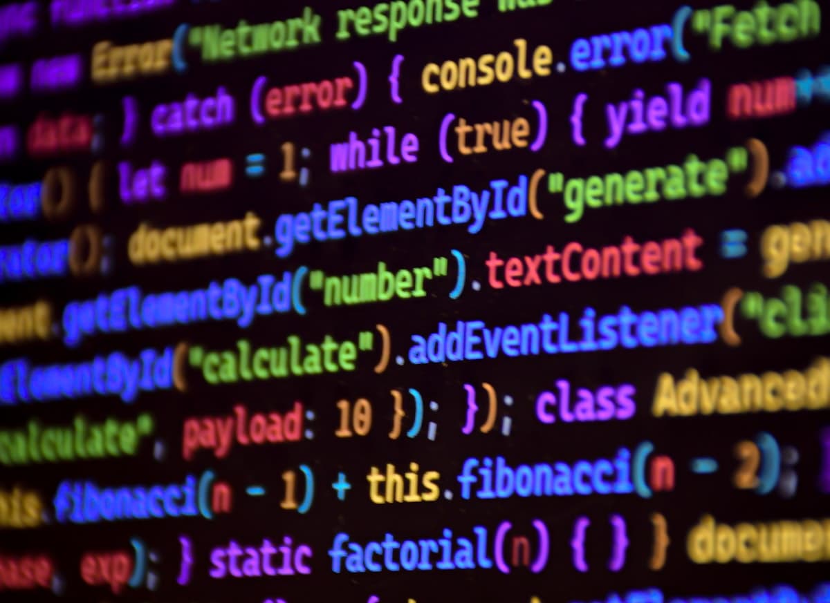 Layar komputer menampilkan kode program dengan syntax highlighting berwarna-warni di editor teks bertema gelap.