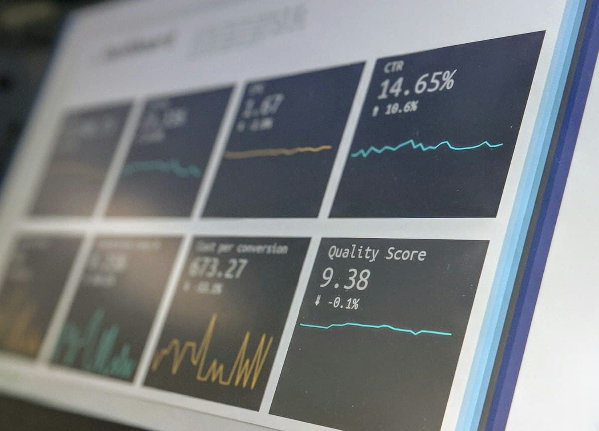 Dashboard data analitik berupa grafik dan angka ditampilkan di layar laptop.